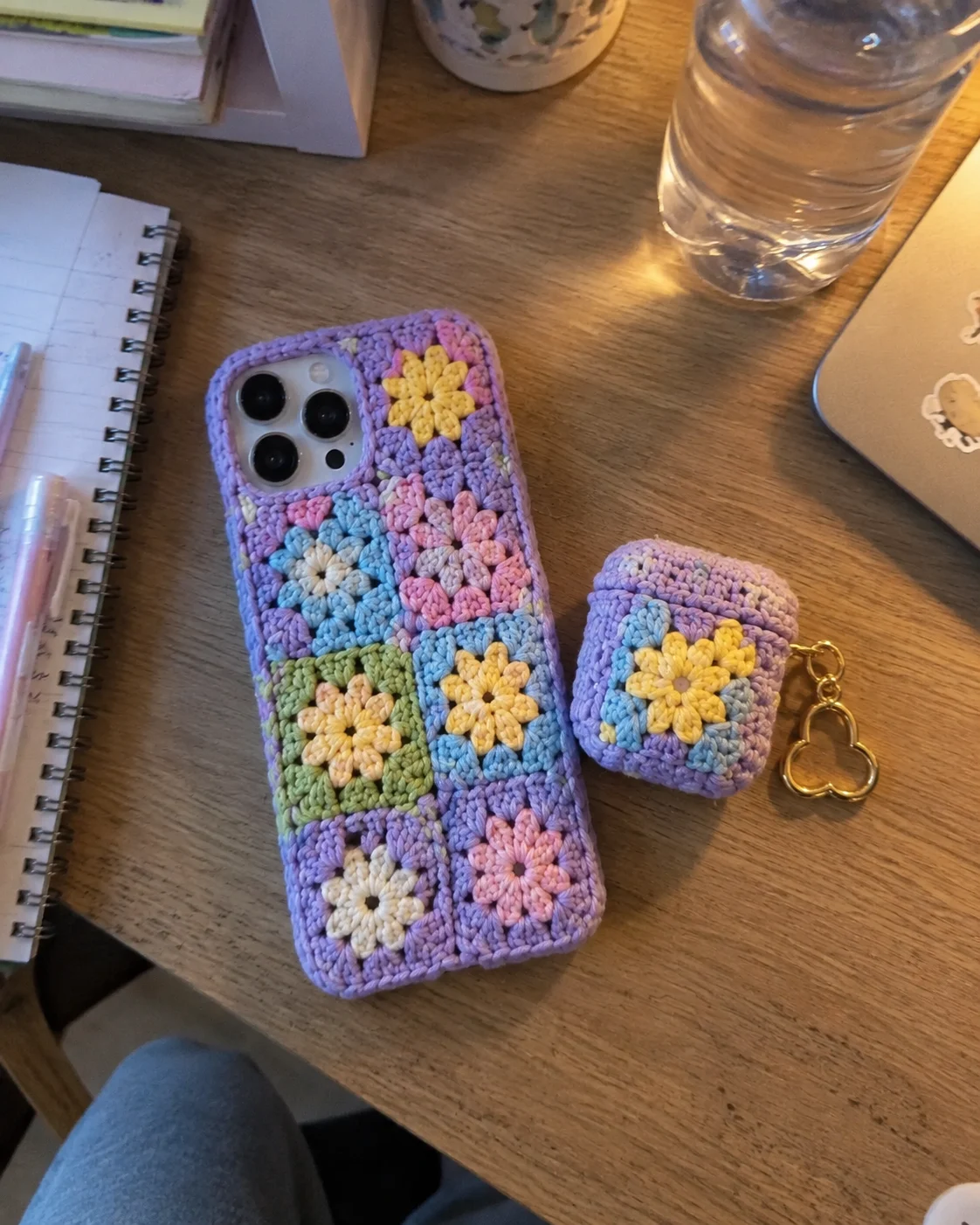 Matching crochet cherry blossom phone and AirPods case held in hand