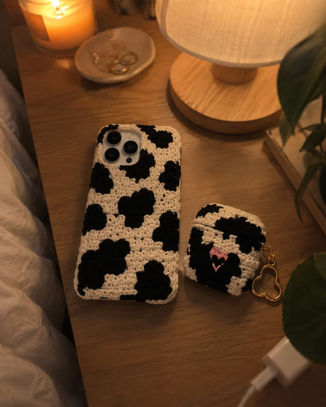 Matching crochet cow print phone and AirPods case on a nightstand